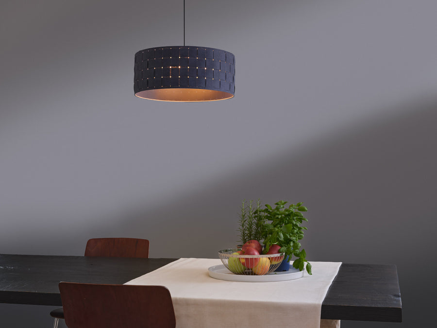 Suspension allumée au-dessus d'une table dressée avec fruits et plantes.