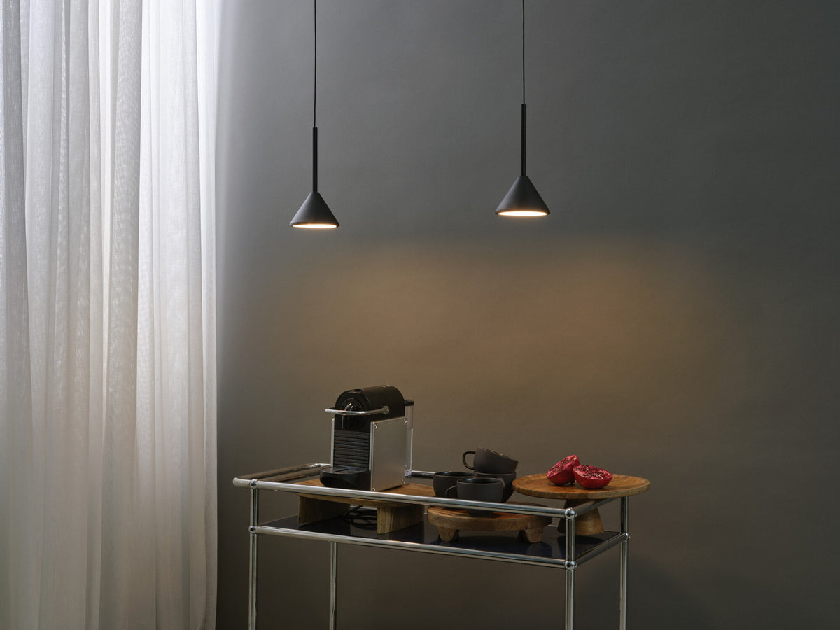Deux suspensions noires éclairent un chariot avec machine à café et tasses