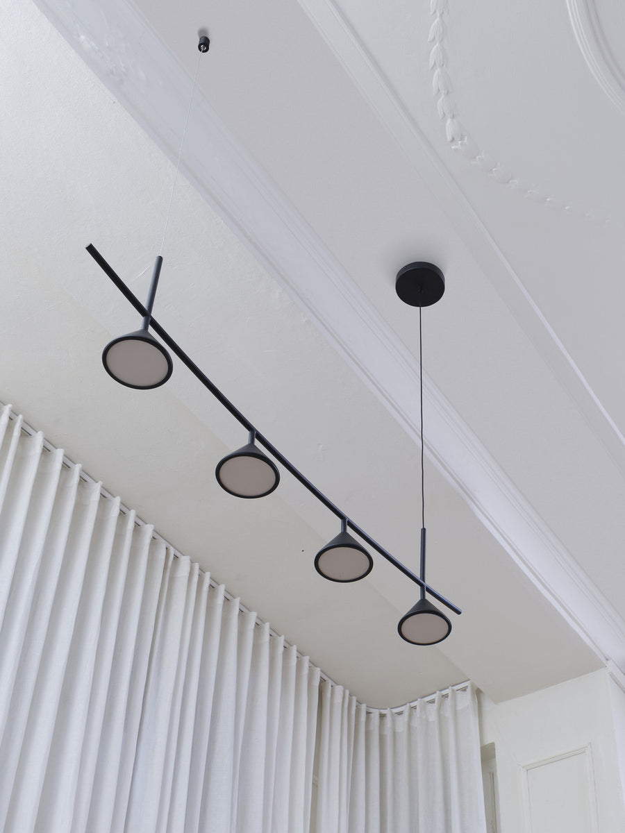 Vue en contre-plongée montrant les câbles et fixations au plafond, barre noire et quatre cônes.