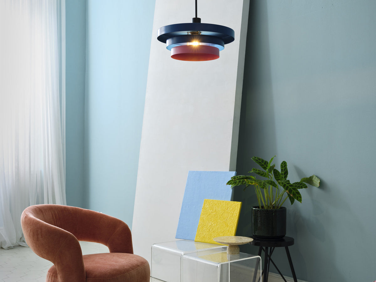 Mise en ambiance salon avec suspension allumée et fauteuil rose