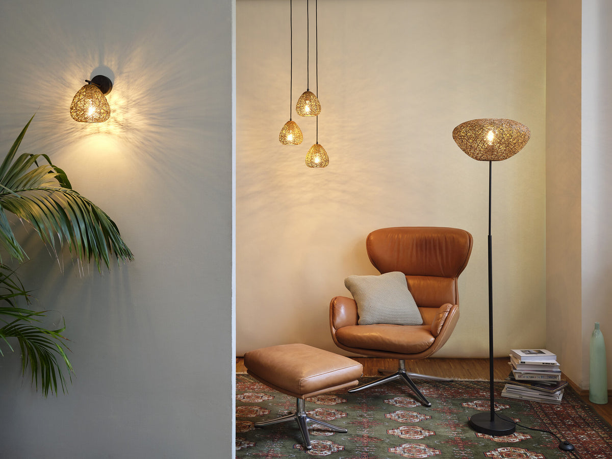 Mise en ambiance avec suspension, applique murale et lampadaire, coin salon chaleureux.