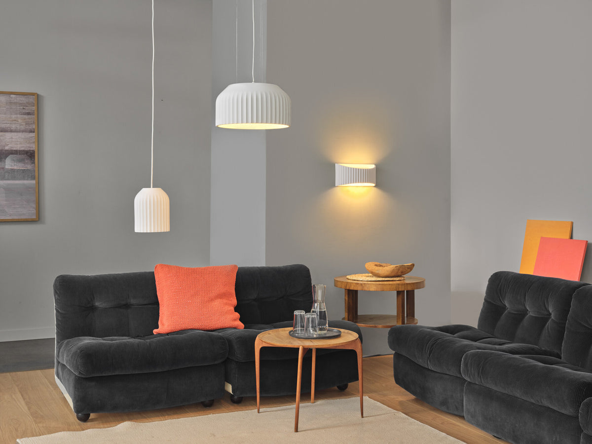 Mise en ambiance dans un salon avec deux suspensions blanches et une applique murale.