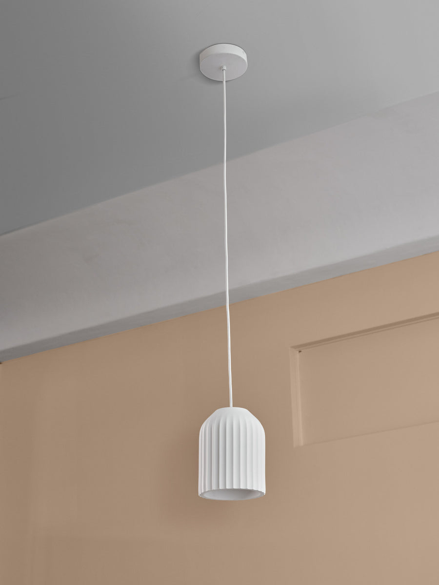 Détail du câble et de la rosace fixés au plafond beige.