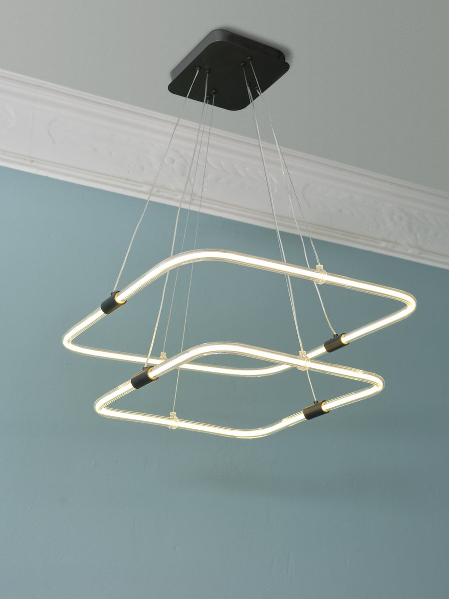 Vue rapprochée du plafonnier suspendu avec câbles fins et finitions noires.