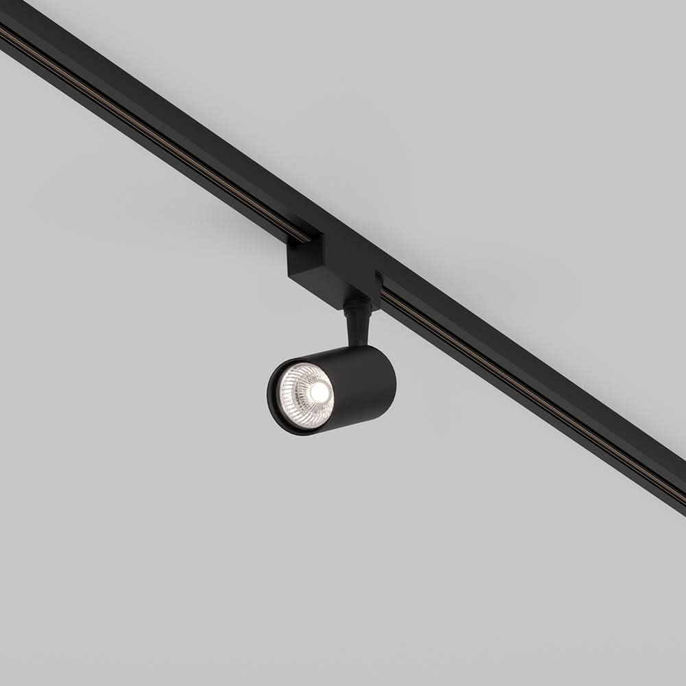 Spot noir cylindrique fixé sur rail de plafond, orientable, vu de trois quarts.