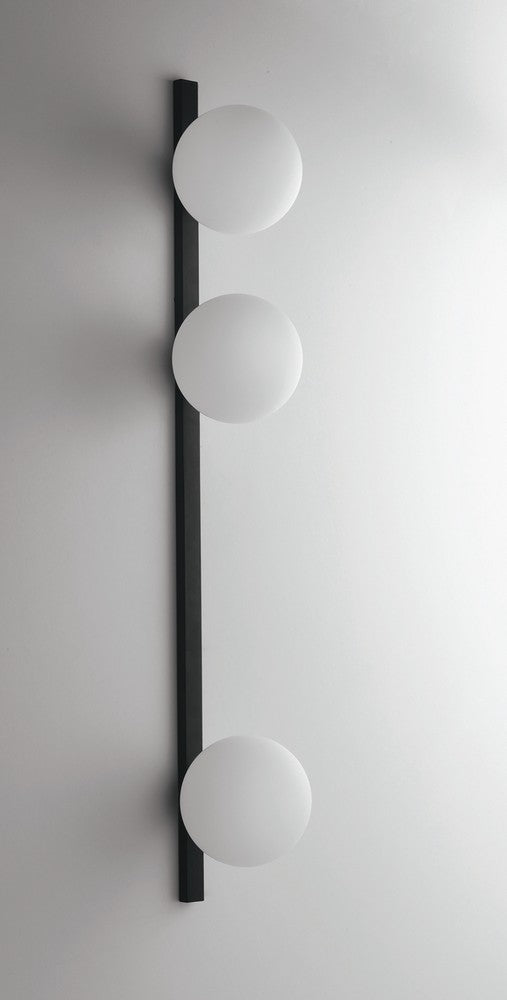 Gros plan sur la barre noire et les globes blancs montés sur un mur clair.