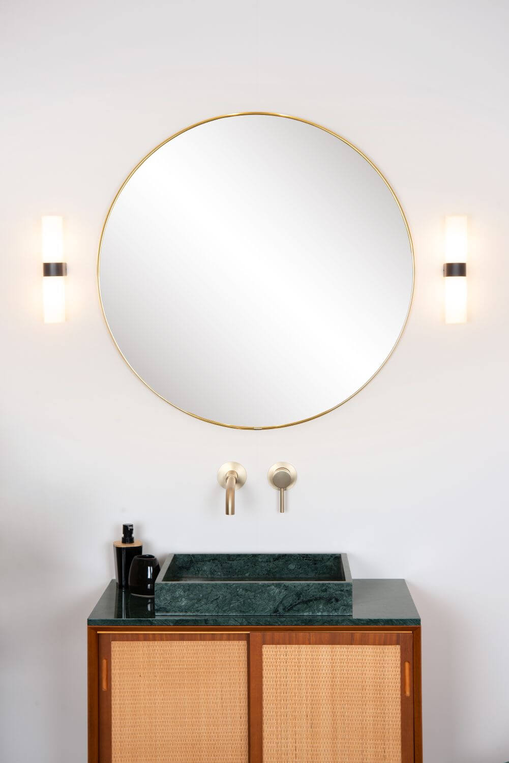 Produit de face, deux appliques cylindriques éclairées encadrant un miroir rond doré
