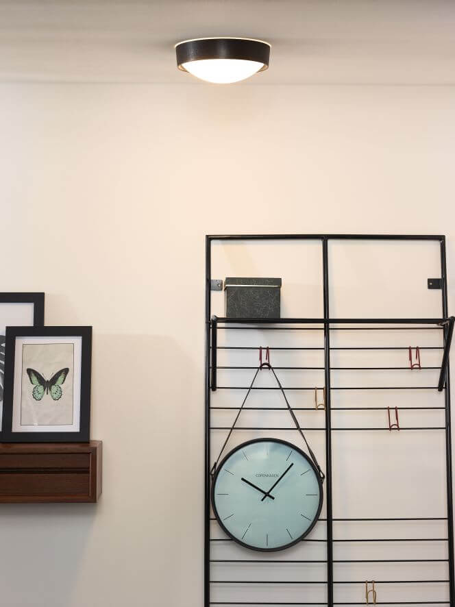 Vue rapprochée du luminaire fixé au plafond, pièce claire avec cadre et étagère
