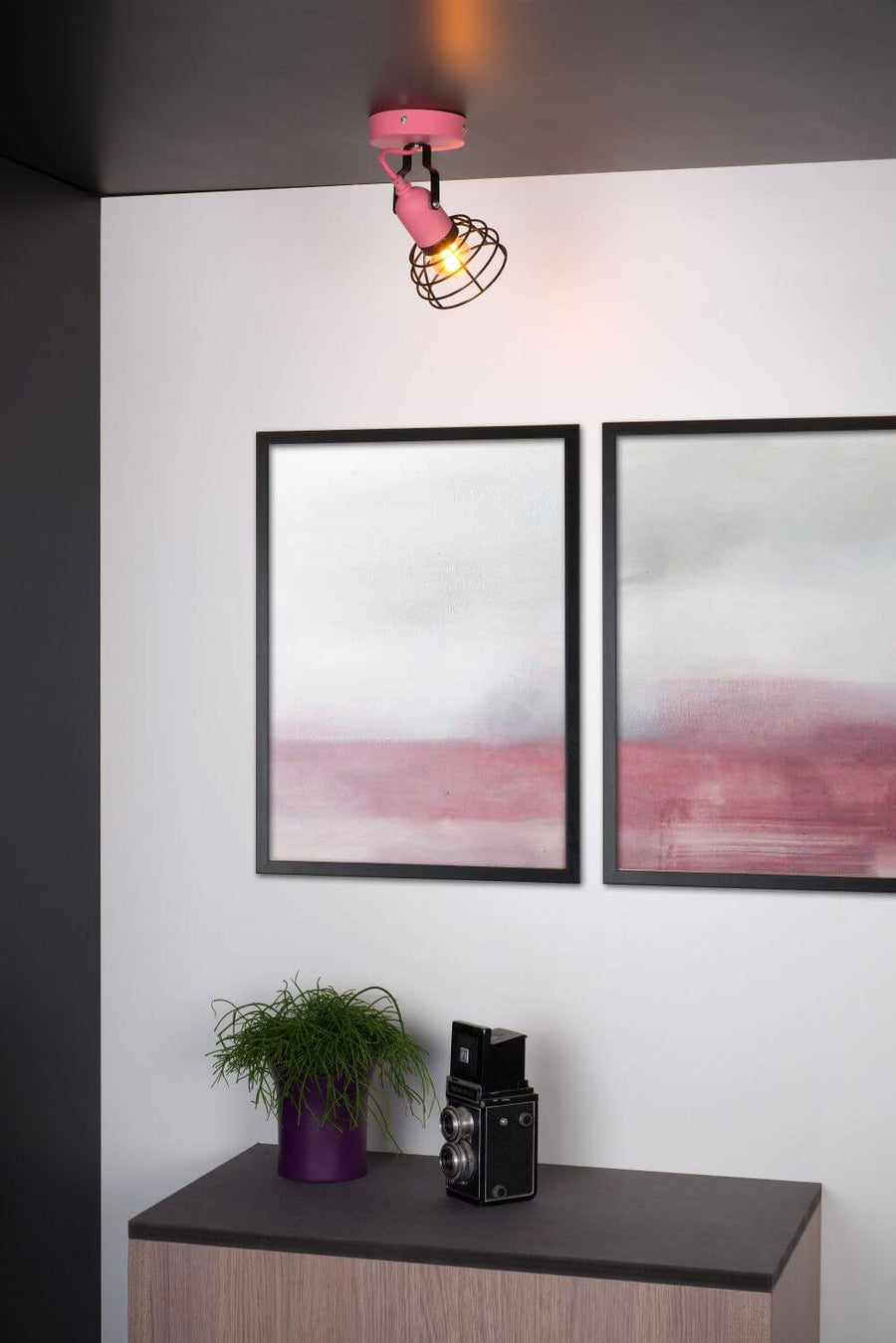 Vue rapprochée du plafonnier rose dans un intérieur avec meubles et cadre