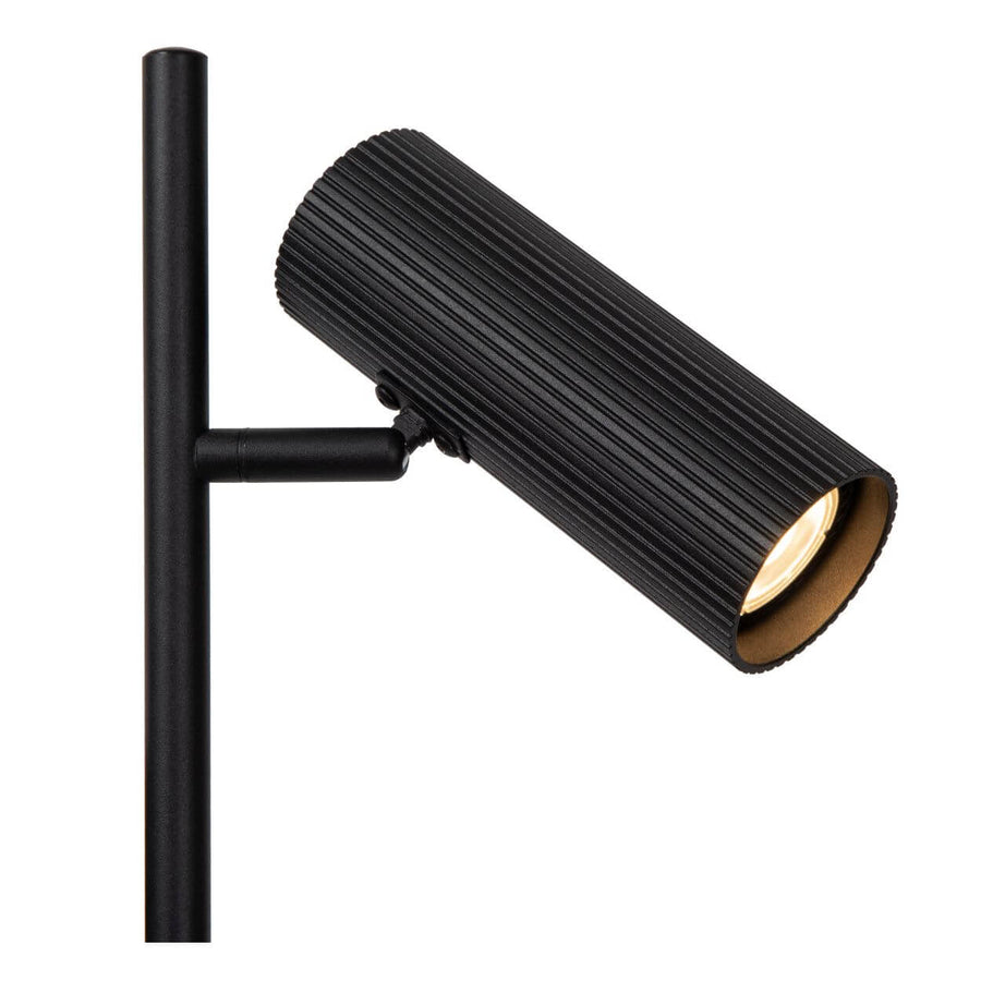 Détail d'une tête de spot cylindrique noire striée, intérieur doré et fixation.
