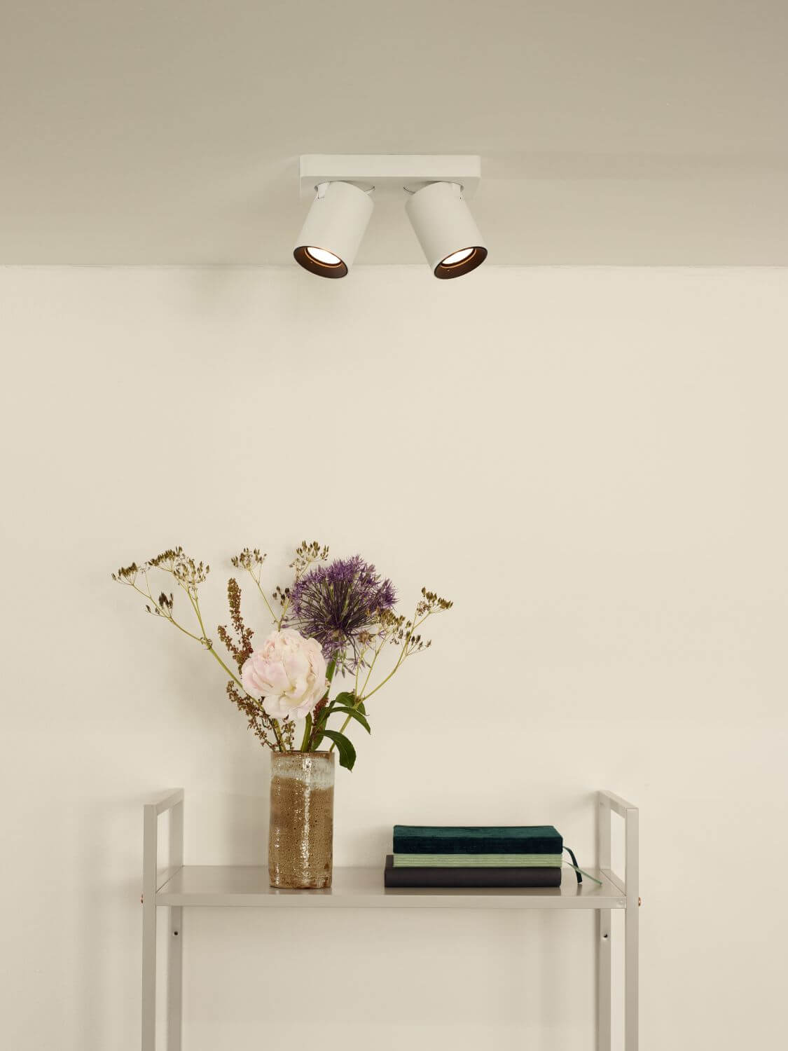 Mise en ambiance du plafonnier blanc allumé au-dessus d'une étagère avec vase fleuri