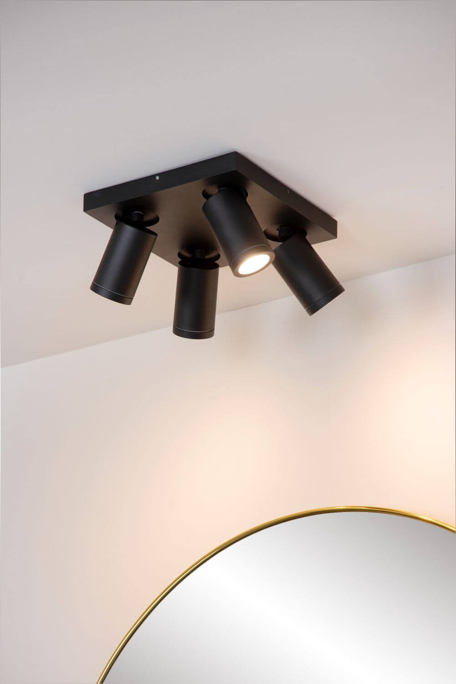 Gros plan sous le plafond avec un projecteur du luminaire noir éclairant la cloison.