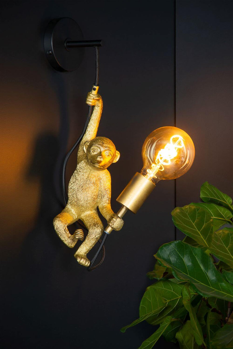 Plan rapproché du singe doré et de son ampoule vintage allumée