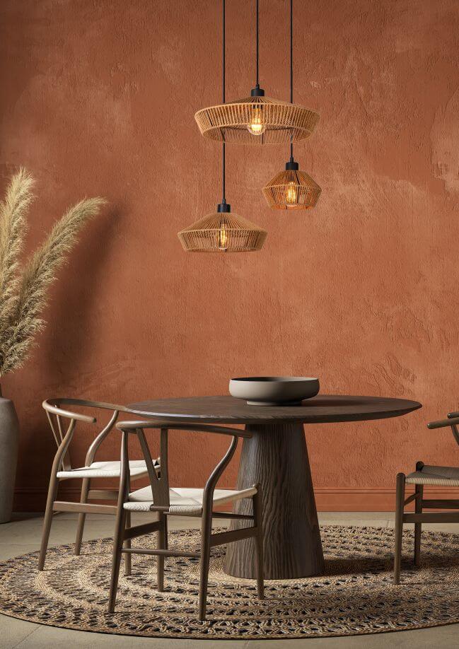 Ambiance chaleureuse mur ocre avec suspension en rotin et chaises en bois clair