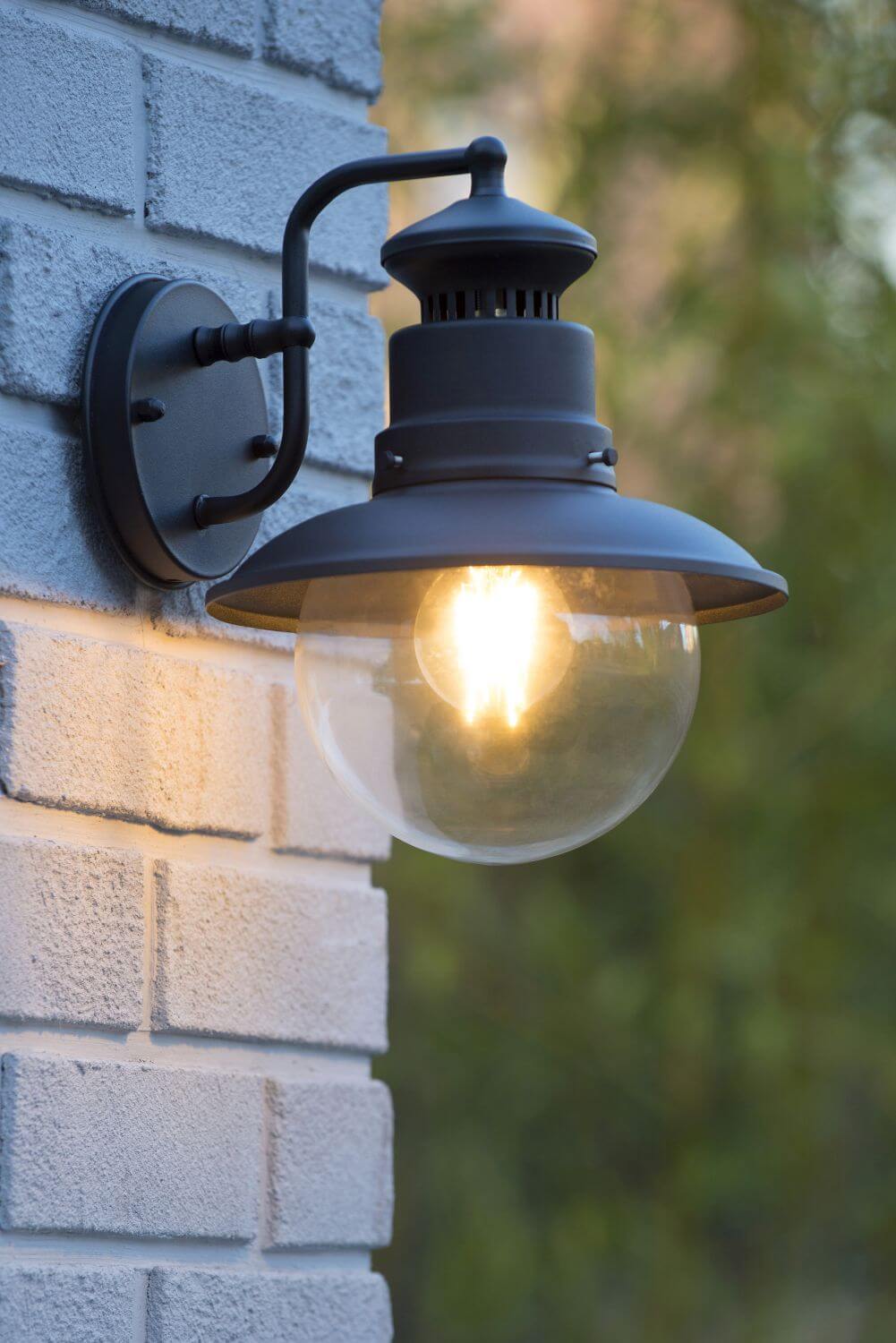 Gros plan de face sur le luminaire allumé, abat-jour métallique et globe verre