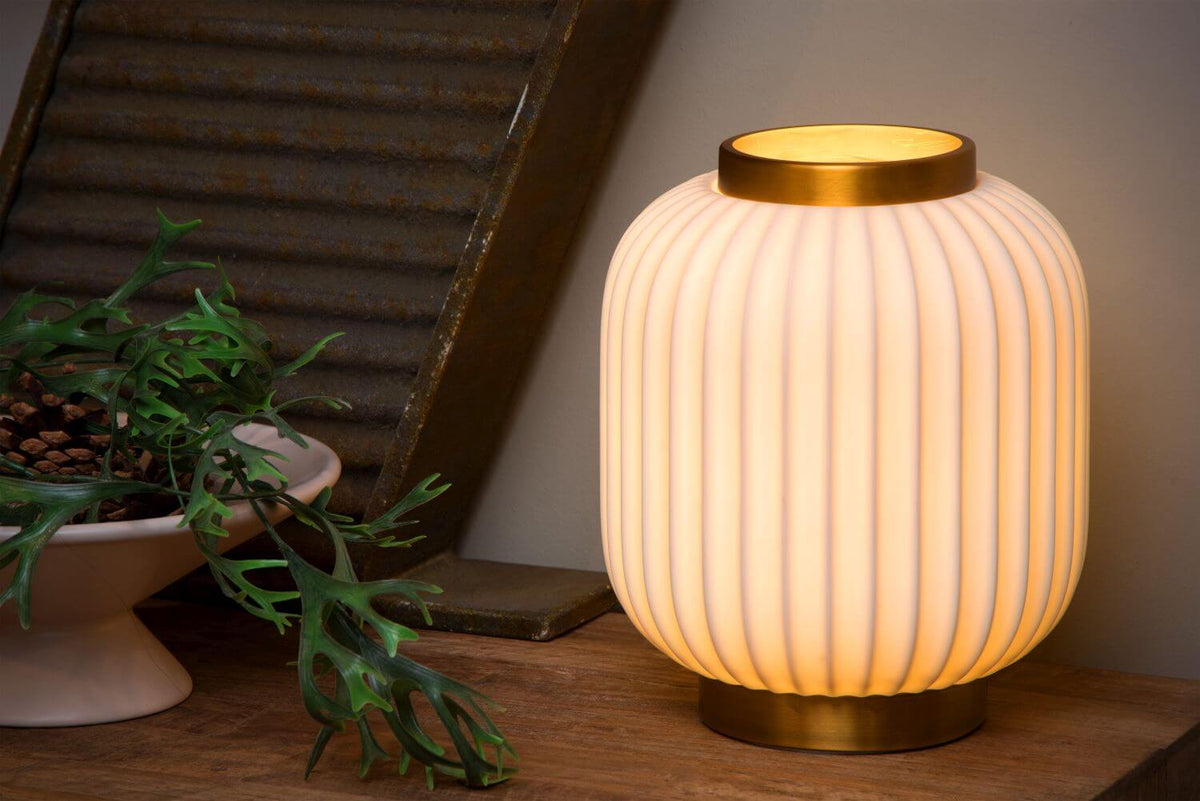 Vue rapprochée de la lampe en porcelaine allumée, posée sur une table en bois