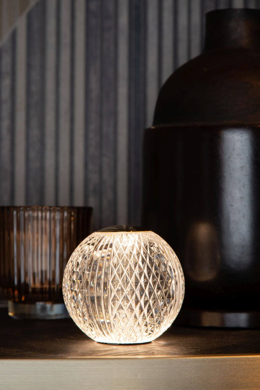 Gros plan rapproché du luminaire allumé sur un meuble sombre, lumière chaude.