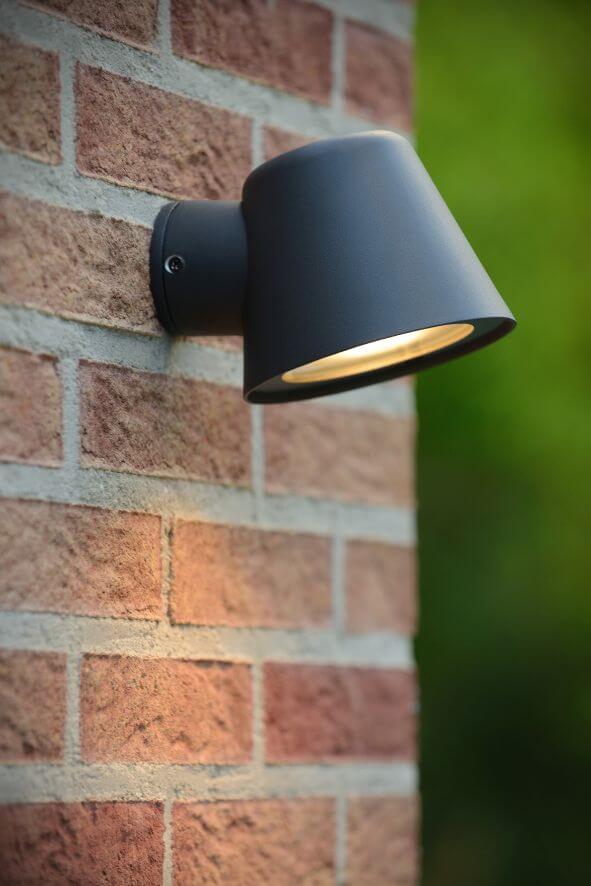 Vue rapprochée du luminaire noir sur brique, cône incliné vers le sol