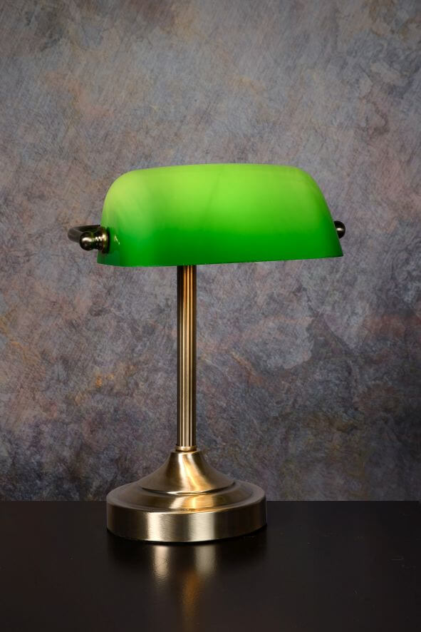 Vue rapprochée de la lampe, abat-jour vert et pied cannelé en laiton.