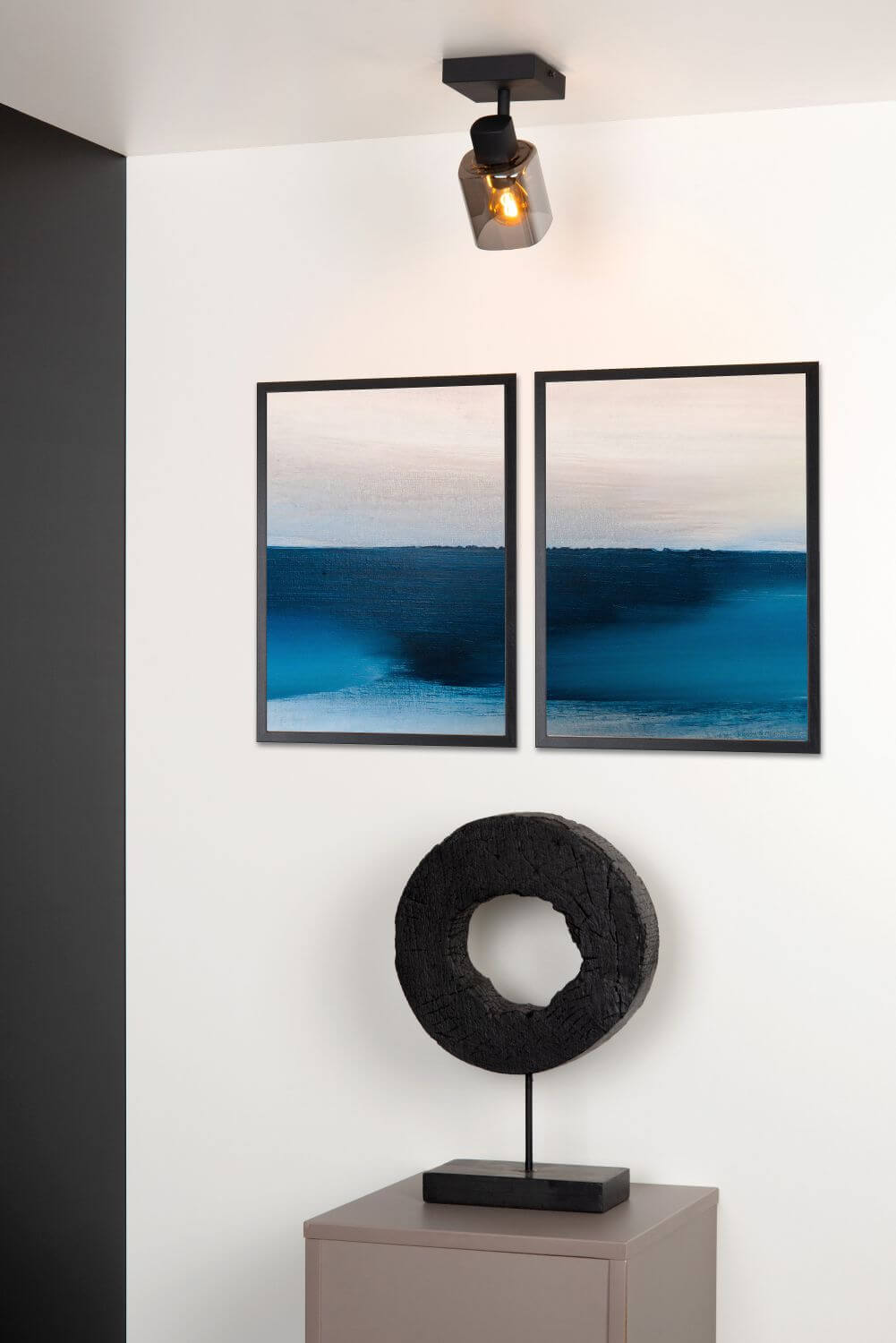 Vue rapprochée du plafonnier allumé, façade blanche, cadres marins et sculpture