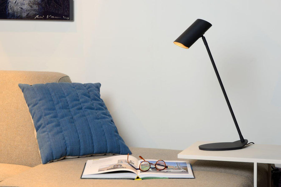 Vue rapprochée de la lampe inclinée, livre et lunettes sur le canapé