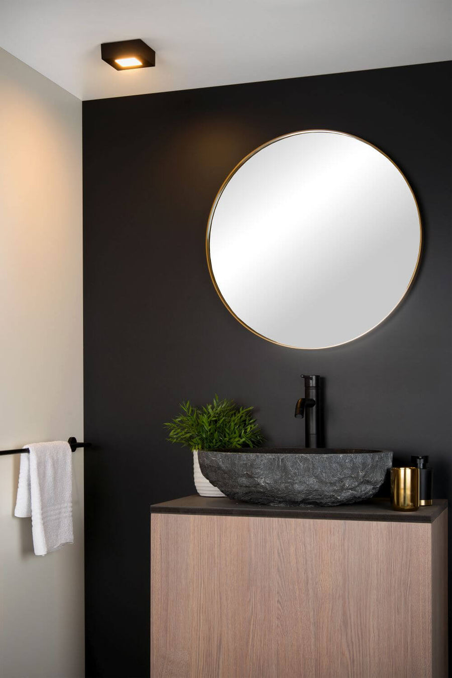 Vue rapprochée du plafonnier noir installé au-dessus du miroir rond