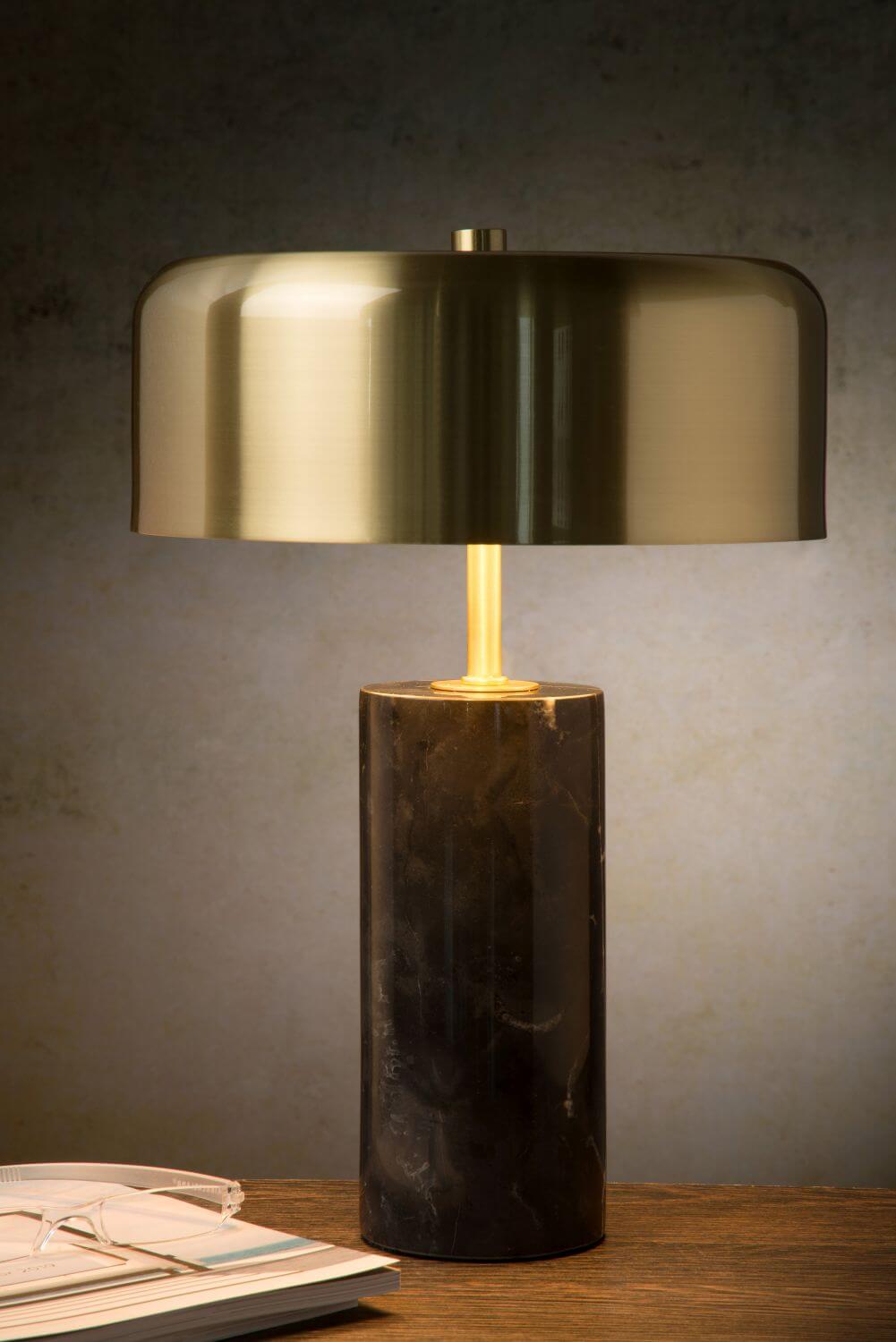 Vue rapprochée du luminaire allumé, abat-jour doré et socle cylindrique en marbre