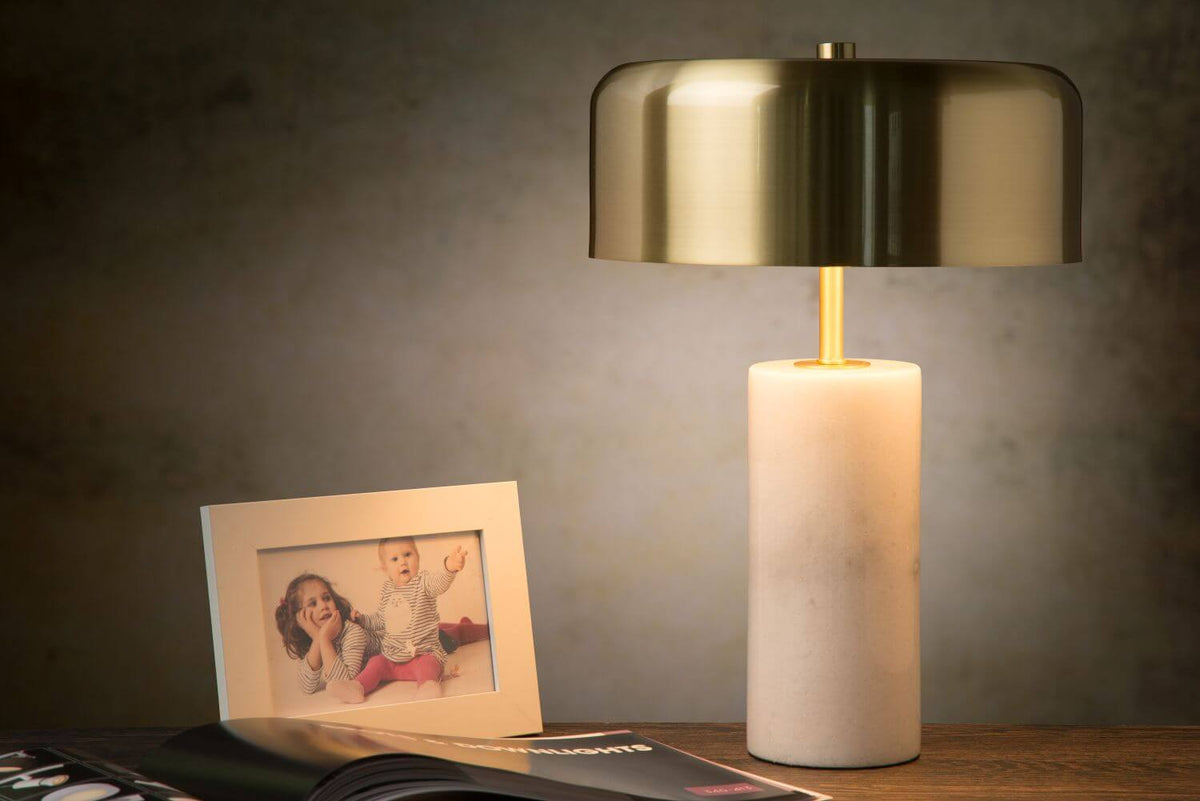 Mise en ambiance chaleureuse avec cadre photo, lampe allumée sur une table en bois.