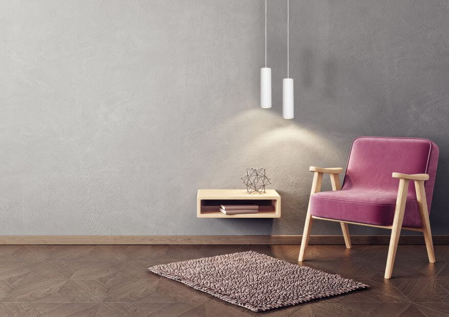 Mise en ambiance avec deux suspensions blanches, table basse murale, fauteuil rose et tapis.
