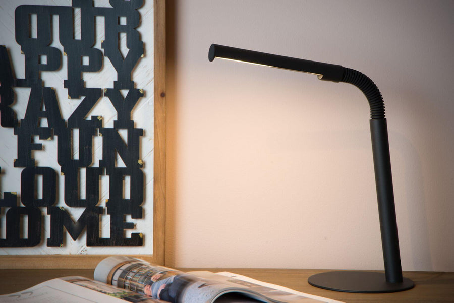 Vue rapprochée de la lampe noire allumée, montrant le flexible et le pied