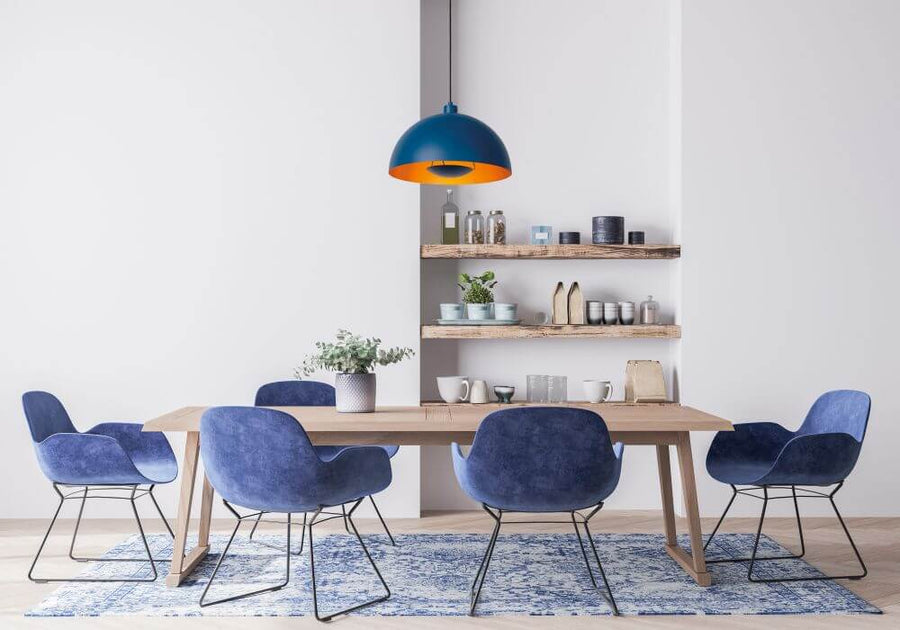 Suspension éclairée au-dessus d'une table à manger entourée de chaises bleues