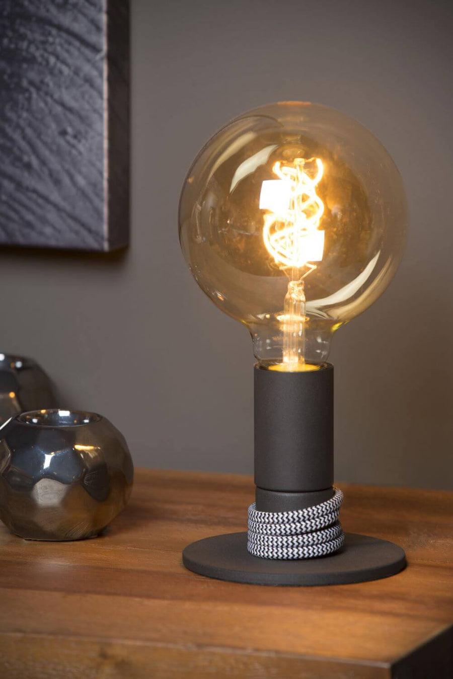 Vue rapprochée de la lampe allumée sur le meuble en bois, ampoule globe visible