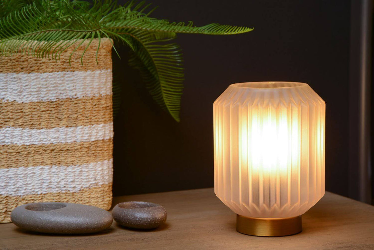 Vue rapprochée du luminaire allumé posé sur un meuble en bois.