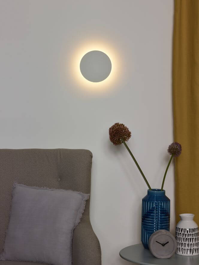 Vue rapprochée de l'applique murale ronde diffusant un halo chaud sur mur