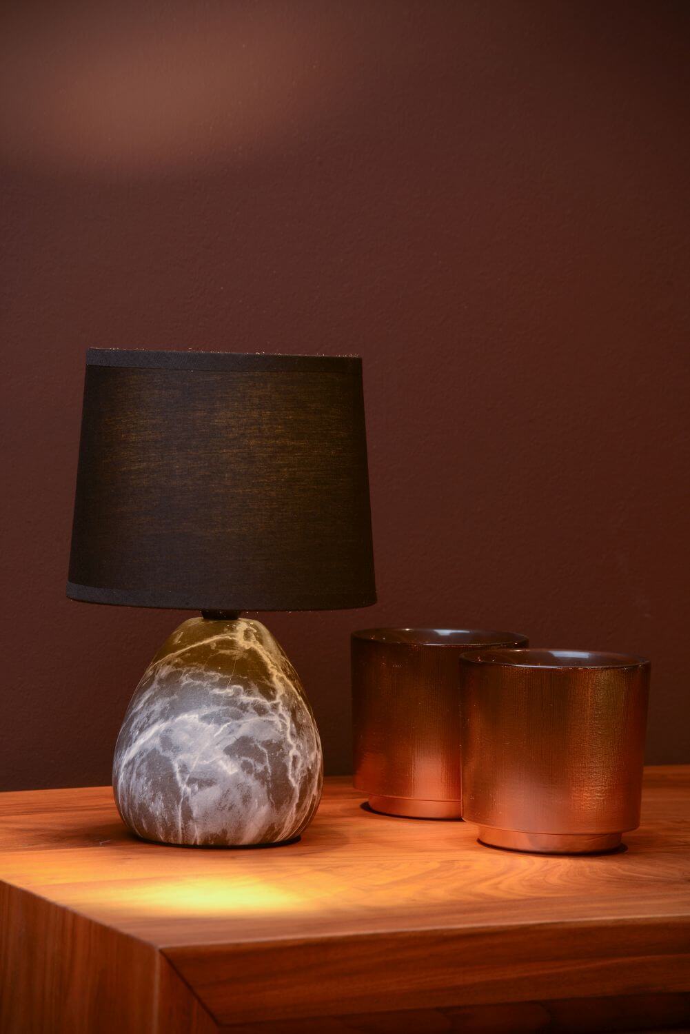 Ambiance chaleureuse : lampe allumée sur une table en bois, près de deux coupelles en cuivre.