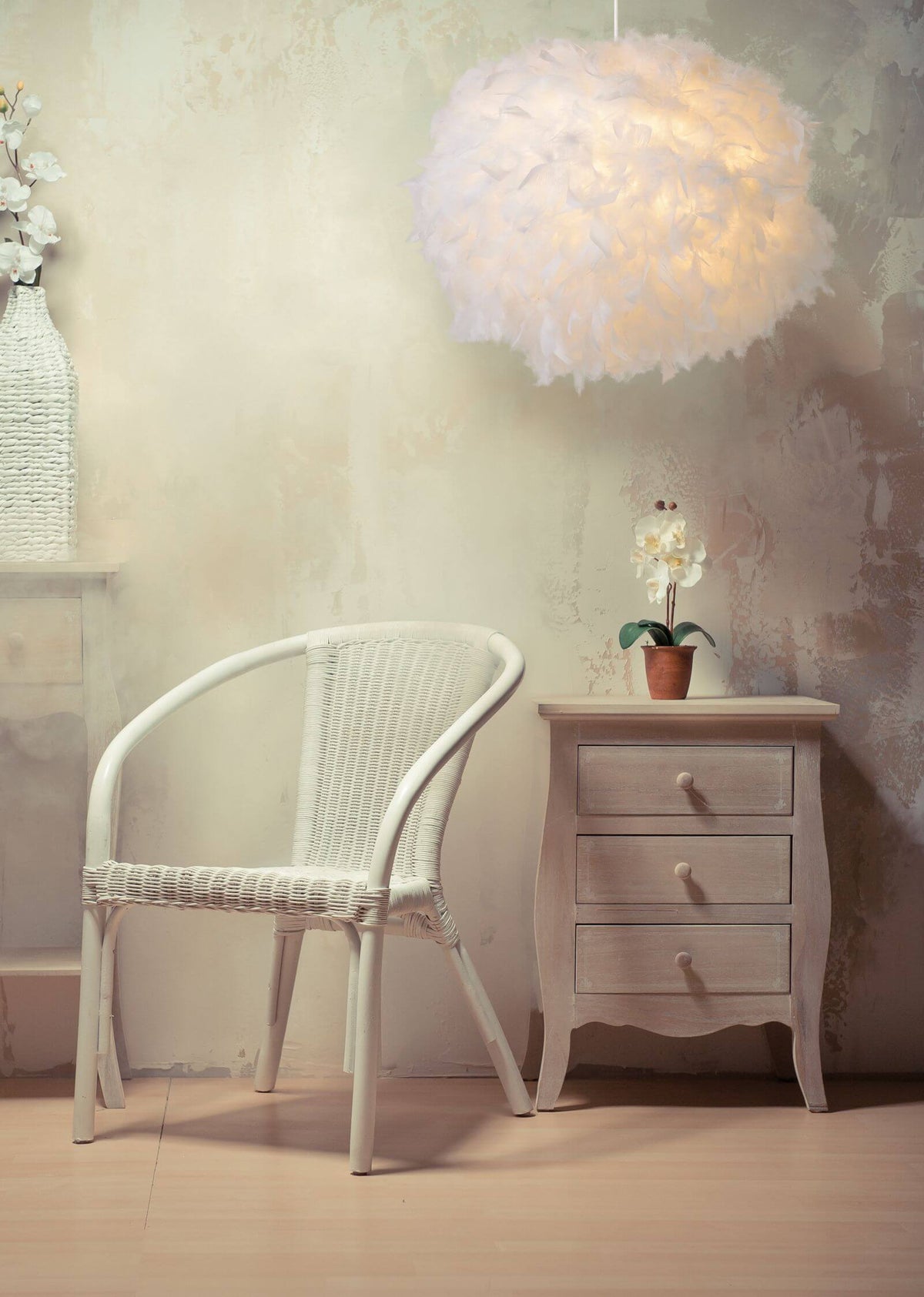 Vue rapprochée du luminaire en plumes allumé dans un intérieur doux avec fauteuil en rotin.