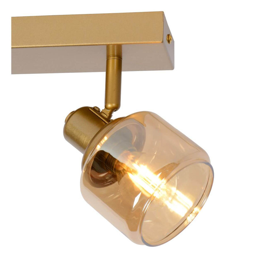Détail serré d'un spot orientable, verre ambré et ampoule allumée en gros plan.
