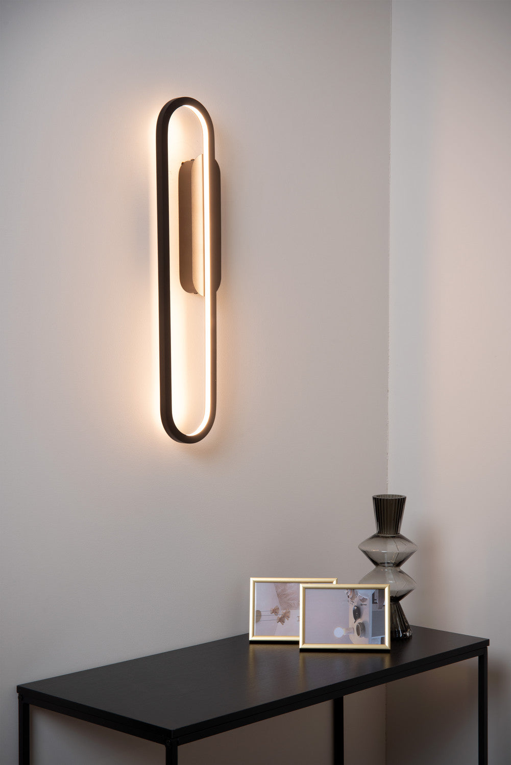 Vue d'ambiance rapprochée du luminaire mural éclairé dans un intérieur sobre et minimaliste