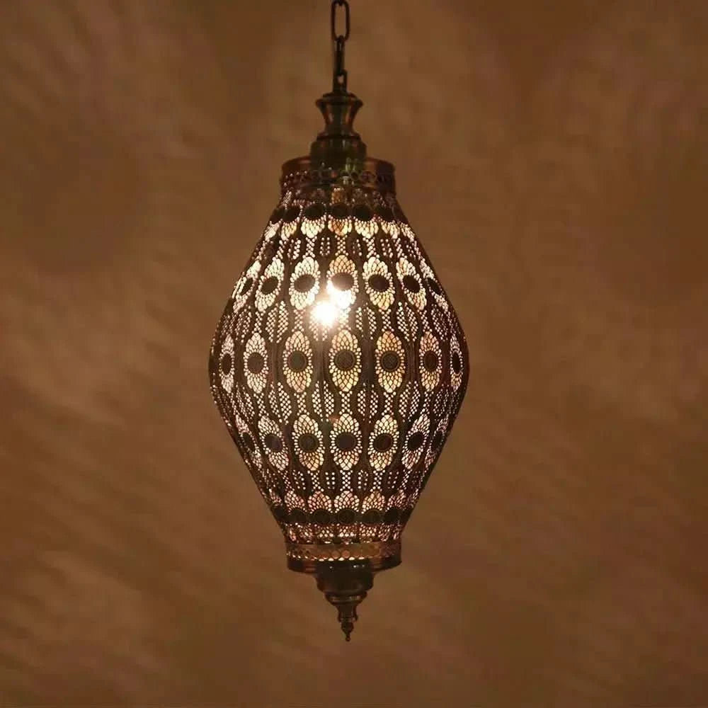 Luminaire suspendu en métal ajouré, éclairé, présenté de face sur fond beige.