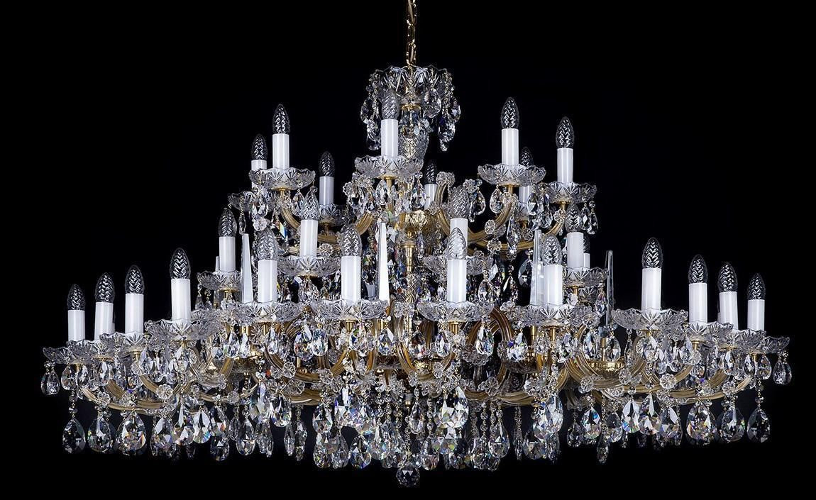 Lustre en cristal de face sur fond noir, monture dorée et nombreux bras