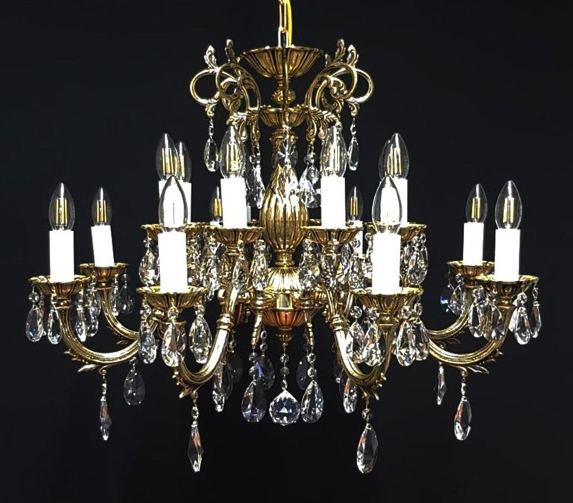 Chandelier doré à huit bras vu de face, ampoules allumées et pendeloques de cristal.