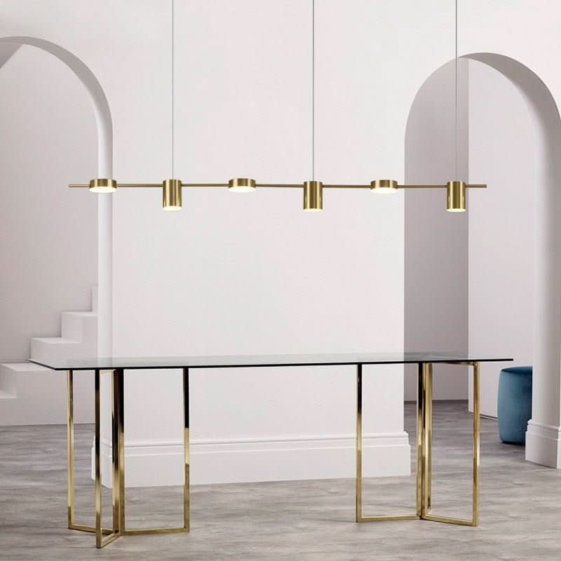 Version dorée du luminaire linéaire présentée devant deux arches blanches