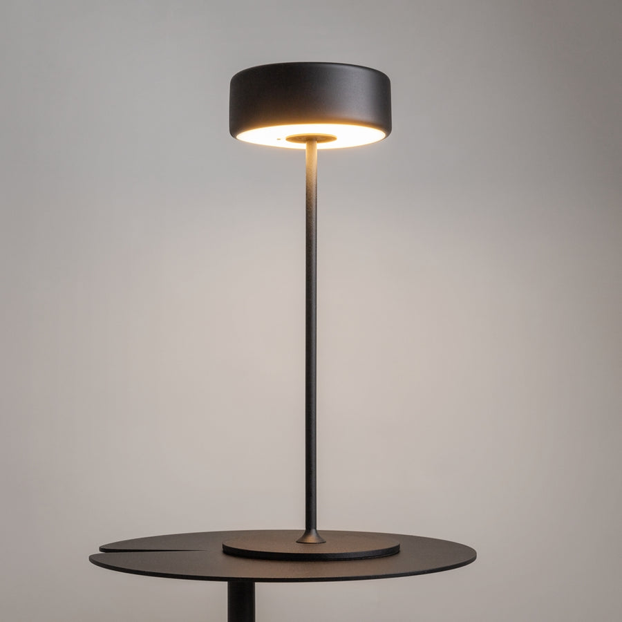 Lampe allumée posée sur une table ronde, halo lumineux diffus vers le bas