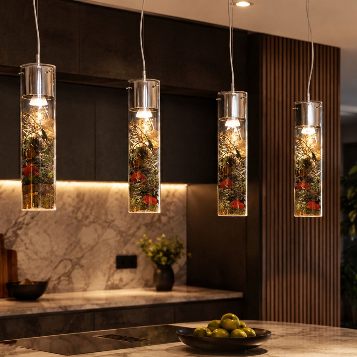 Quatre luminaires cylindriques contenant des fleurs séchées colorées au-dessus d'un plan de travail en marbre.
