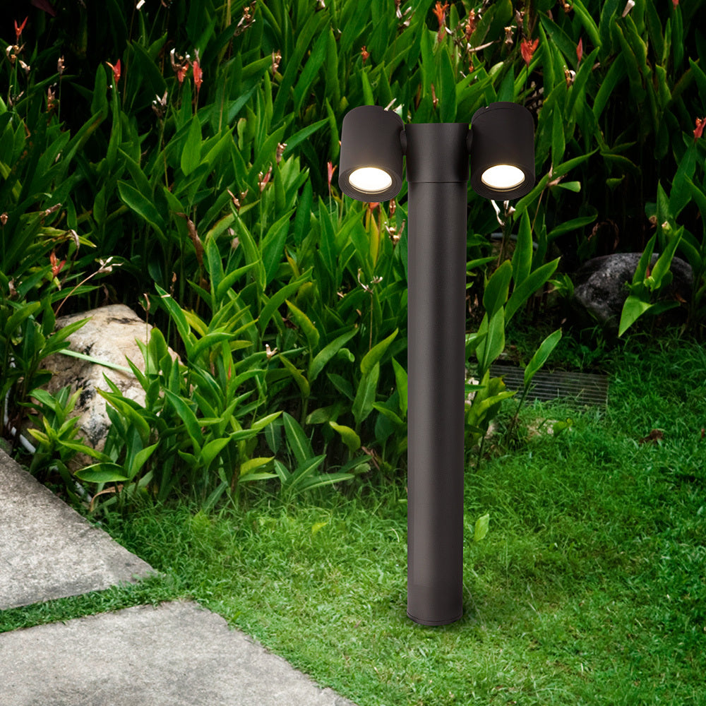 Borne noire installée dans un jardin, éclairant des plantes vertes et une allée