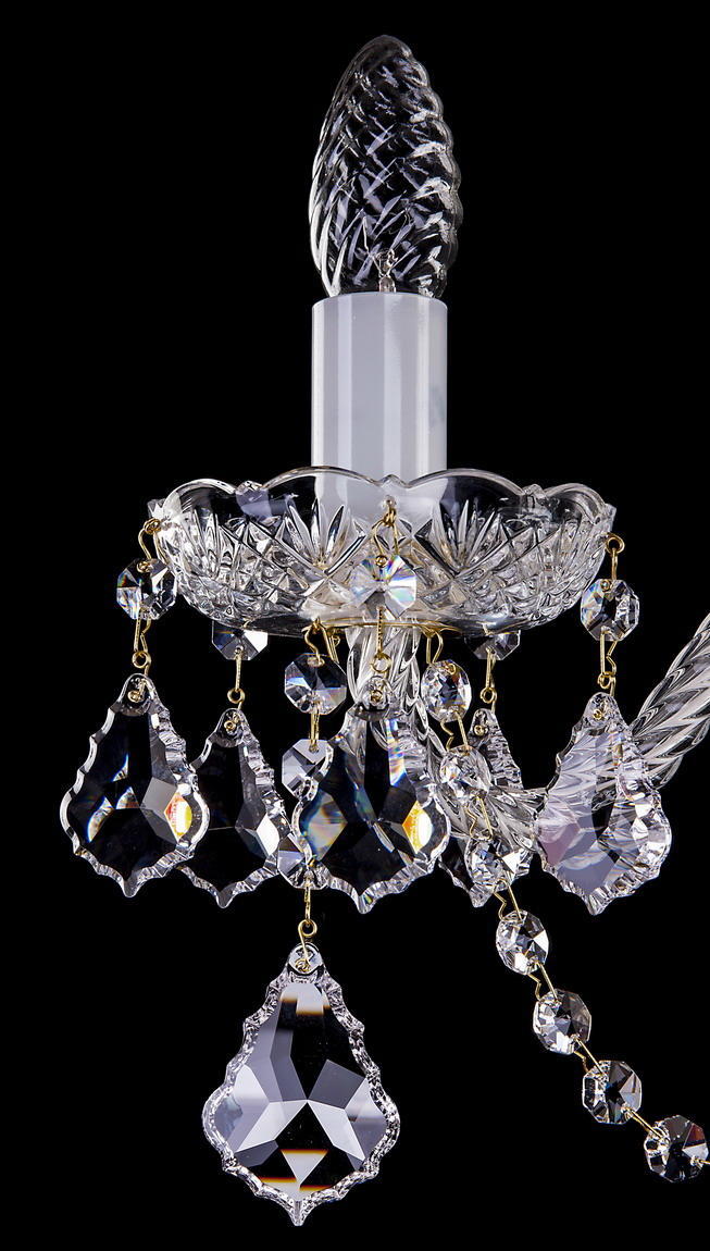 Gros plan sur une bobèche ciselée et ses pendeloques de cristal suspendues.