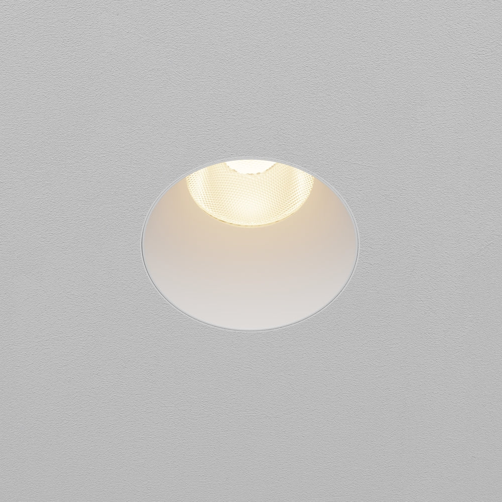 Spot encastré blanc allumé, vu de face dans un plafond texturé