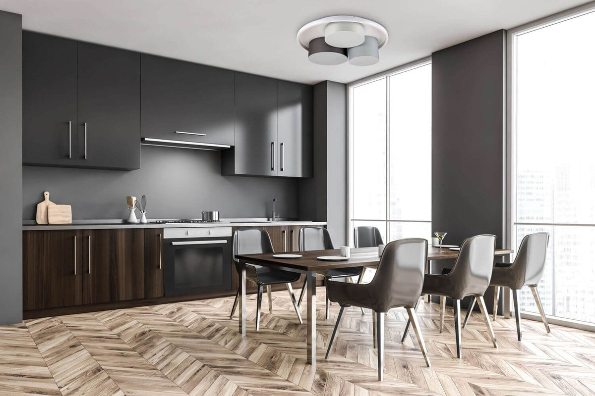 Mise en ambiance d'une cuisine moderne sombre, plafonnier gris fixé au plafond au-dessus de la table