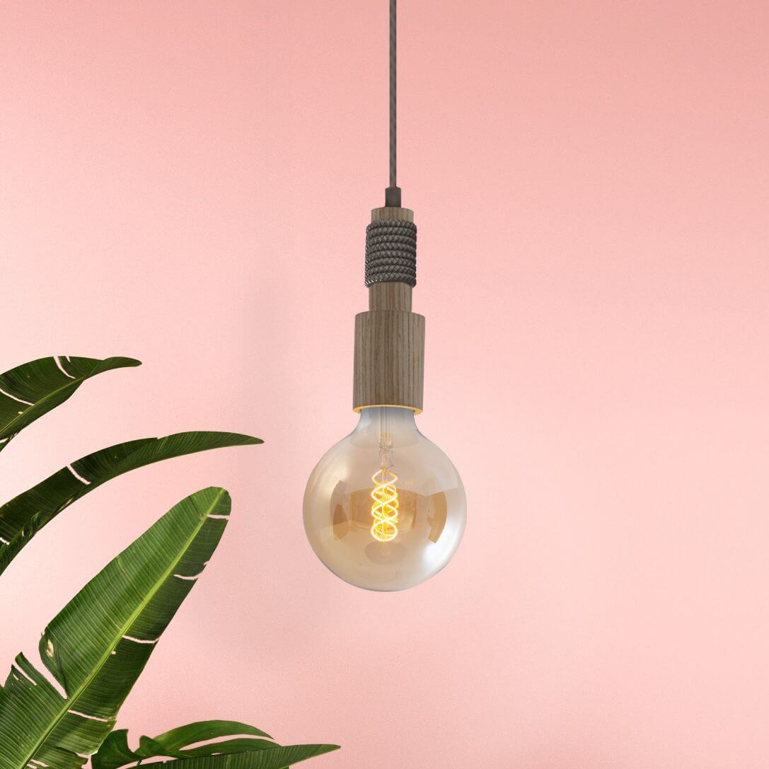Gros plan sur la douille en bois et l'ampoule à filament, fond rose