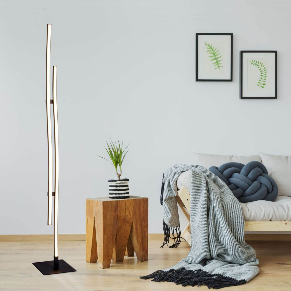 Lampadaire allumé dans un salon déco avec table en bois et plante verte